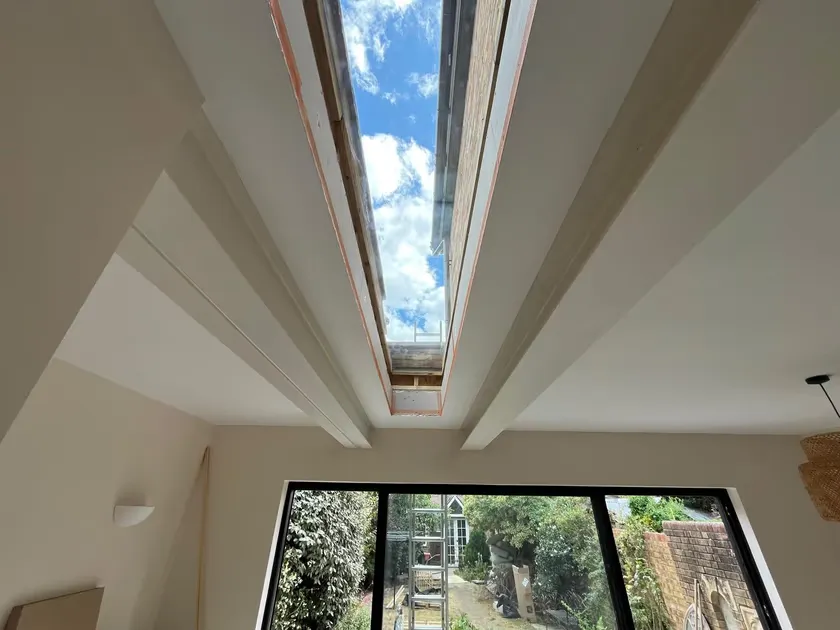 Finished long flat glass rooflight in a new rear extension ceiling, with blue sky above and garden doors below