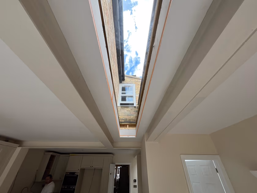 Glazed rooflight seen from inside the extension with the kitchen below and daylight filling the room