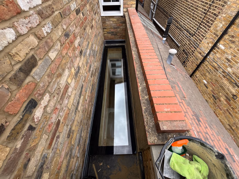 Flat glass rooflight installed on the extension roof, viewed along its length from the scaffold