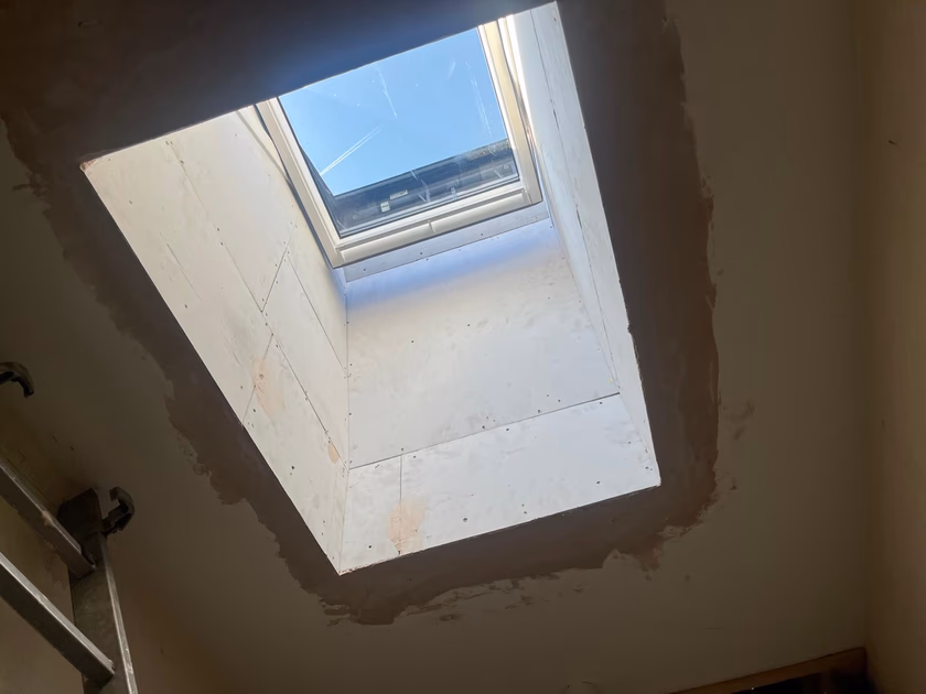 View up through the boarded light shaft to the new Velux roof window and blue sky