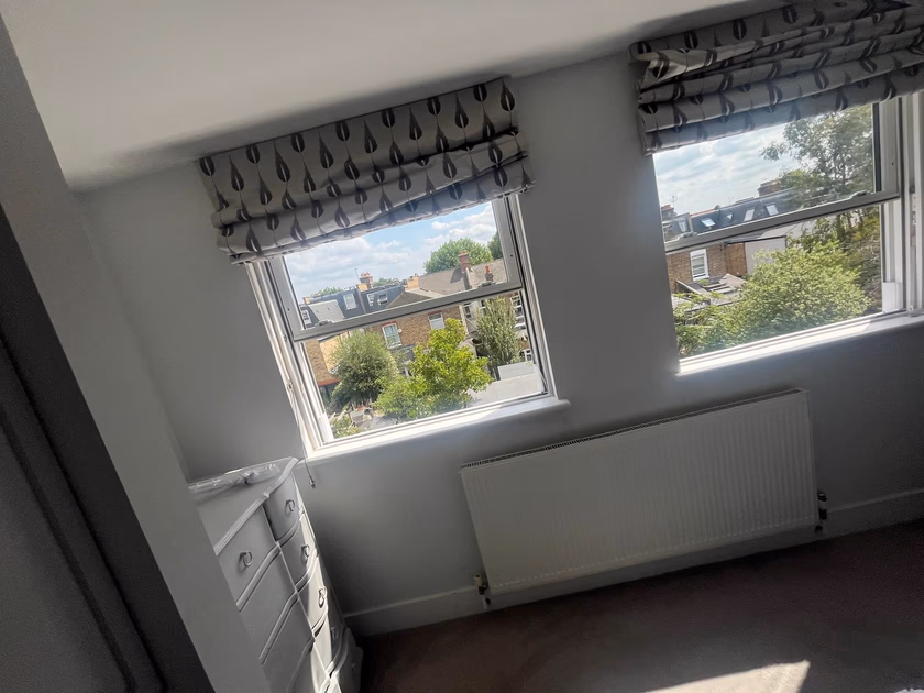 The two new sash windows fitted side by side in the bedroom, with blinds rehung and radiator below